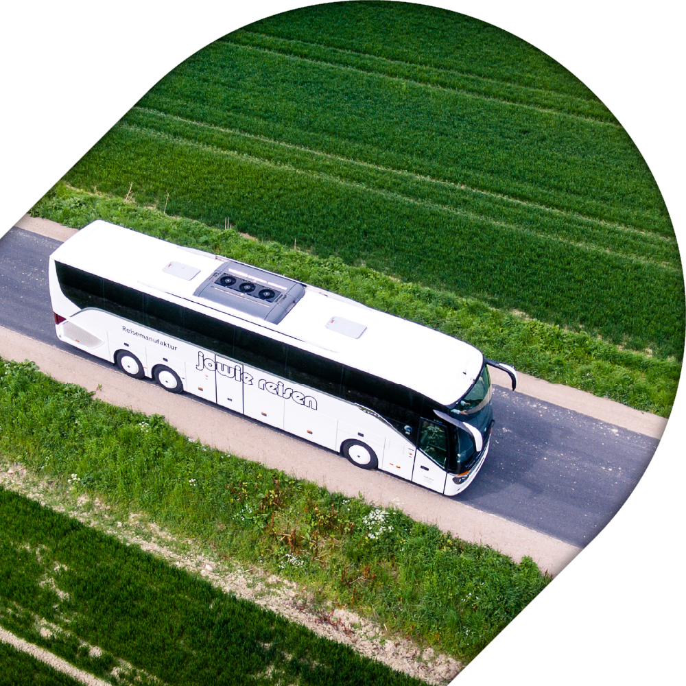 Ein Reisebus von Jowie Reisen fährt auf deiner Landstraße.